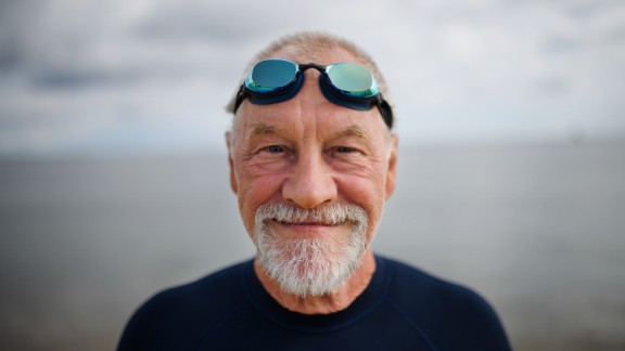 Ældre mand med svømmebriller smiler ved vand