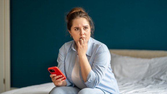 En kvinde holder sin mobil i hånden og ser bekymret ud