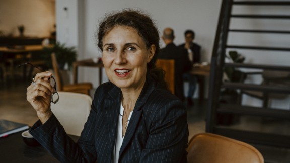 Kvinde holder sine briller og smiler til kamera