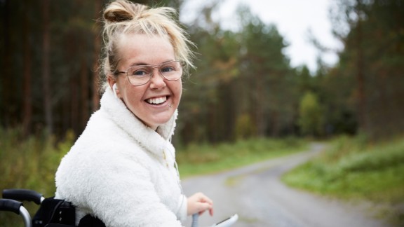 En kvinde i kørestol smiler