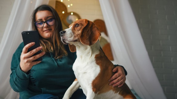 En kvinde kigger på sin mobil og holder sin hund