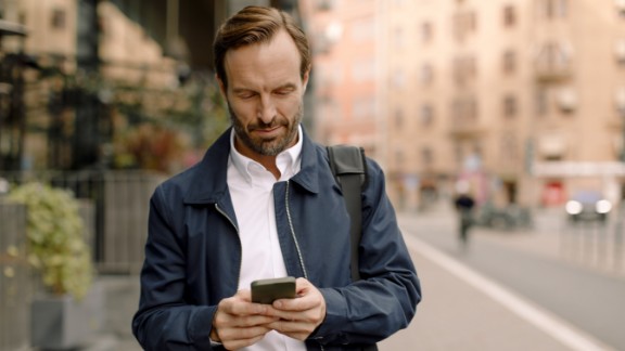 Mand kigger på mobil på gade