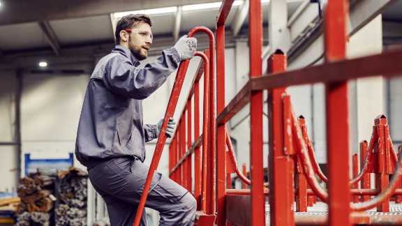 Mand klatrer op ad stige på fabrik