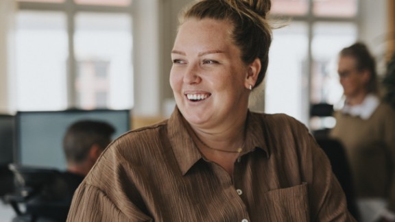 En kvinde i brun skjorte griner