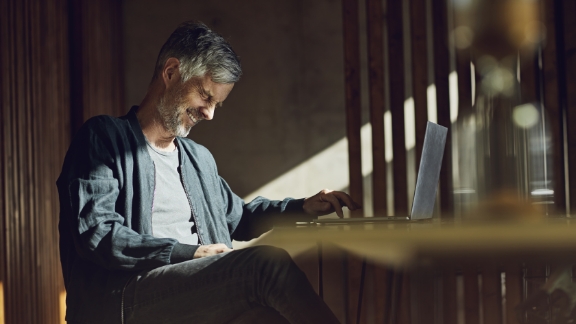 Mand_griner_ved_skrivebord_feature_576x324