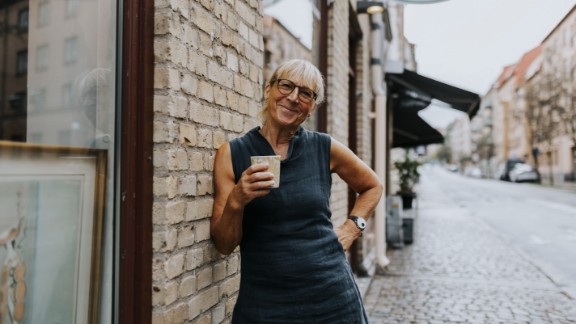 Kvinde med en kop kaffe smiler på gågade