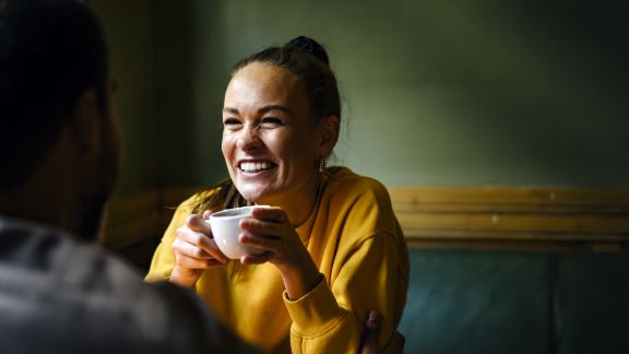 Kvinde_griner_med_kaffe_text-image-50_50_576x324