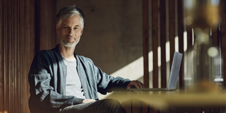 Mand_ved_skrivebord_smiler_content-header_768x384