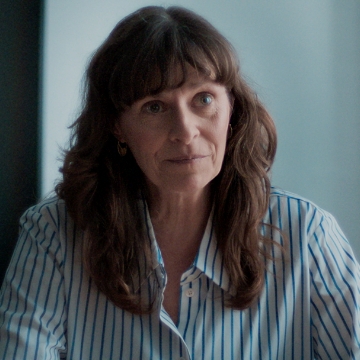 Kvinde i blåstribet skjorte i møde om håndtering af psykiske sygdom på arbejdspladsen.