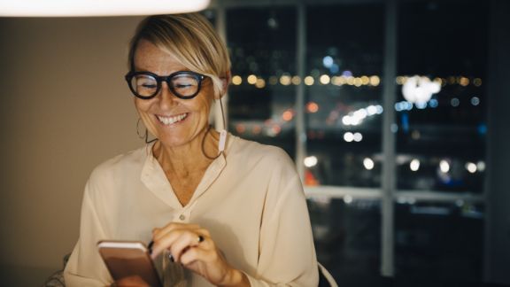 Kvinde_smiler_telefon_aften_article-card_576x324