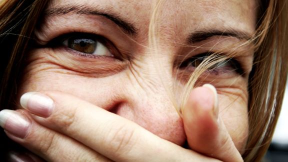 Kvinde_griner_haand_foran_mund_text-image-50_50_576x324