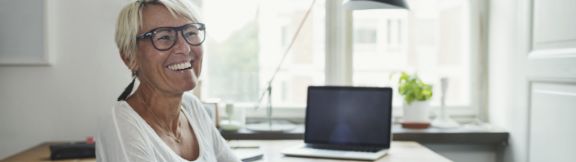 Kvinde_griner_ved_skrivebord_expand-box_576x162