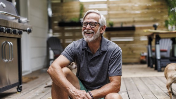 Ældre mand griner på træterrasse 