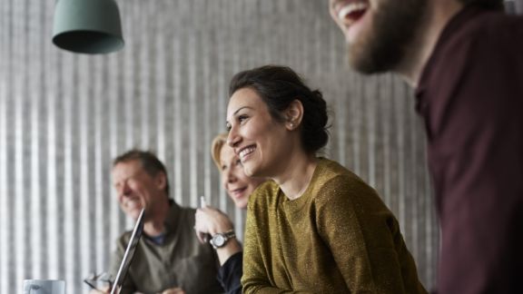 Kvinde_griner_blandt_andre_article-card_576x324