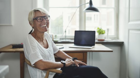 Kvinde_griner_ved_skrivebord_article-card_576x324