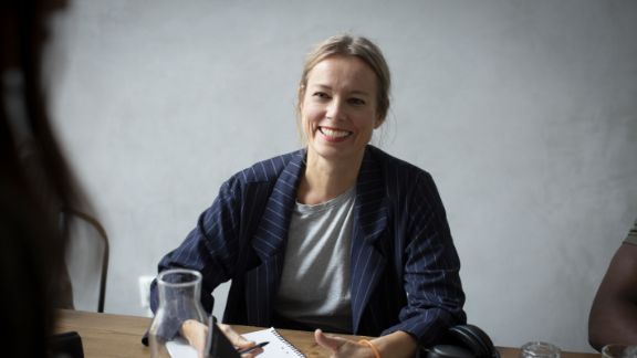 Kvinde_smiler_ved_skrivebord_article-card_576x324