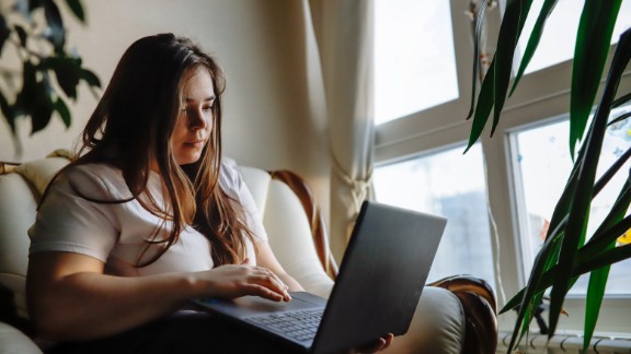 En kvinde sidder med en bærbar på skødet