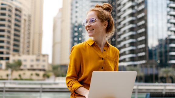 Kvinde_smiler_baenk_computer_article-card_576x324