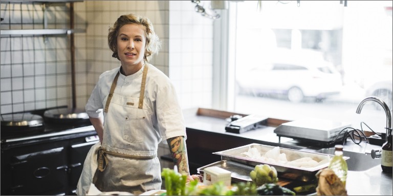 Kvindelig kok står i køkken på restaurant