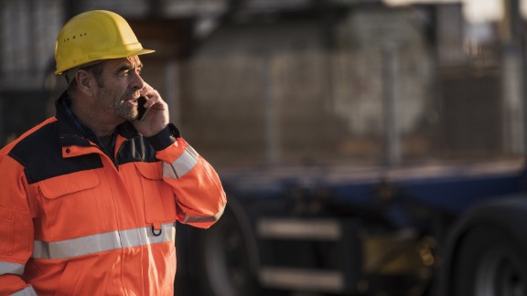 Arbejdsmand med hjelm taler i telefon	
