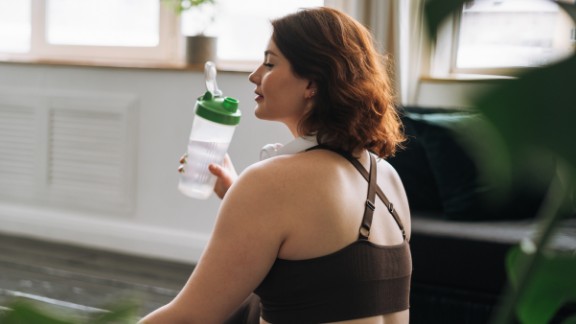 Kvinde drikker af drikkedunk til yoga