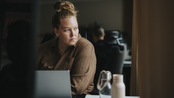 En kvinde sidder foran sin computer og kigger væk