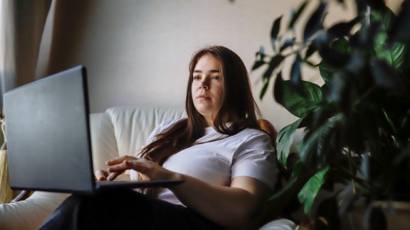 En kvinde sidder med en bærbar på skødet