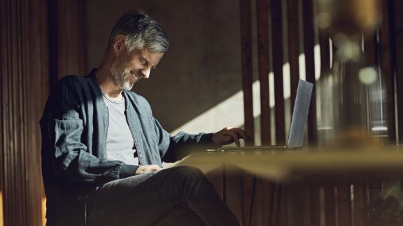 Mand_griner_ved_skrivebord_article-card_576x324