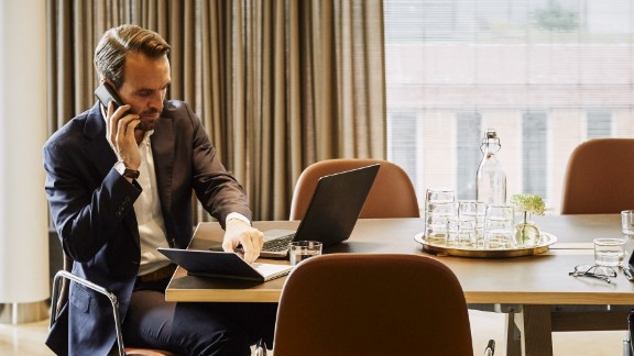 Mand i mødelokale arbejder og taler i telefon