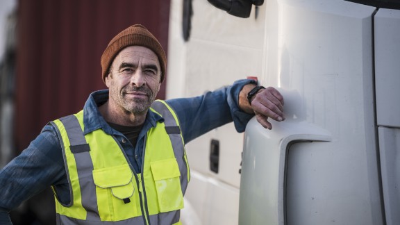 Mand i gul vest læner sig op ad lastbil