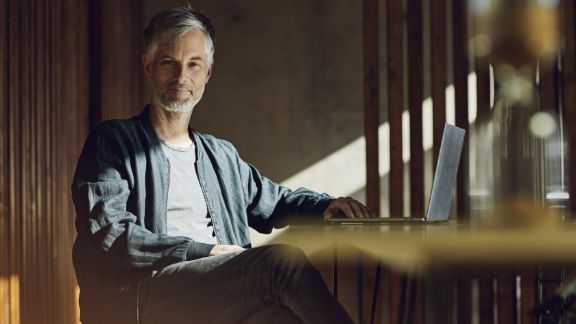 Mand_ved_skrivebord_smiler_article-card_576x324