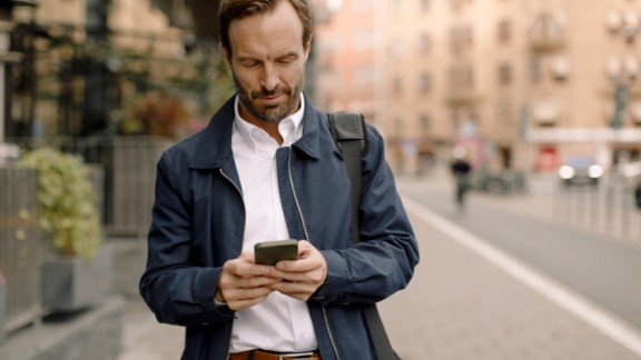 Mand kigger på mobil på gade