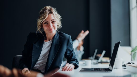 Kvinde_smiler_ved_skrivebord_computer_article-card_576x324